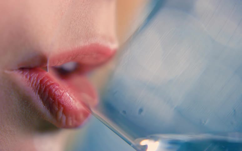 A human face where the lips open to drink water from a glass cup