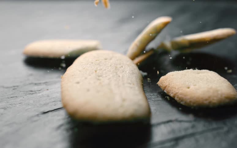 Several cookies falling to the floor and breaking