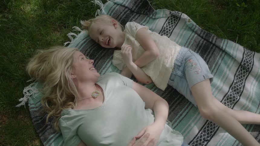 A woman and child lay on a blanket talking