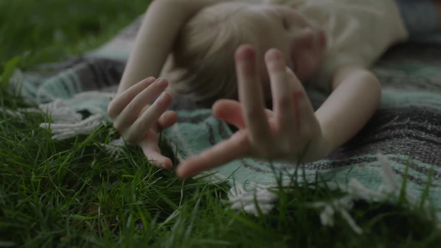 A child is laying on a blanket on the grass