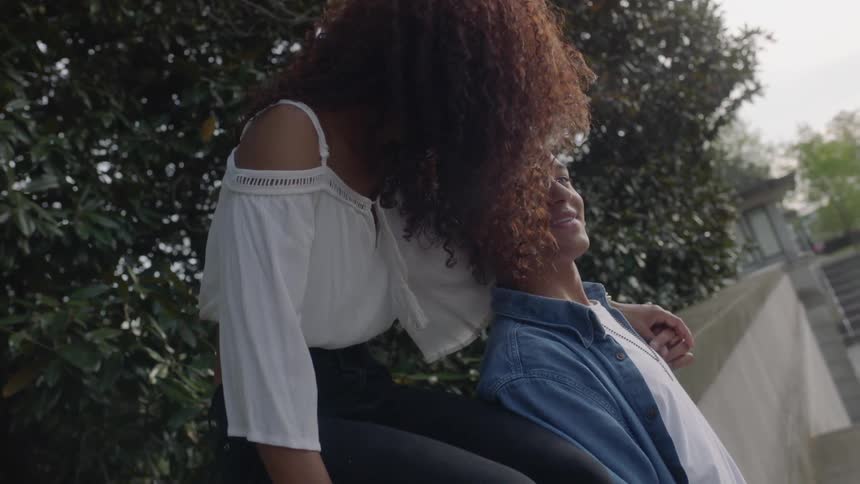 A woman puts her arm around a man below smiling
