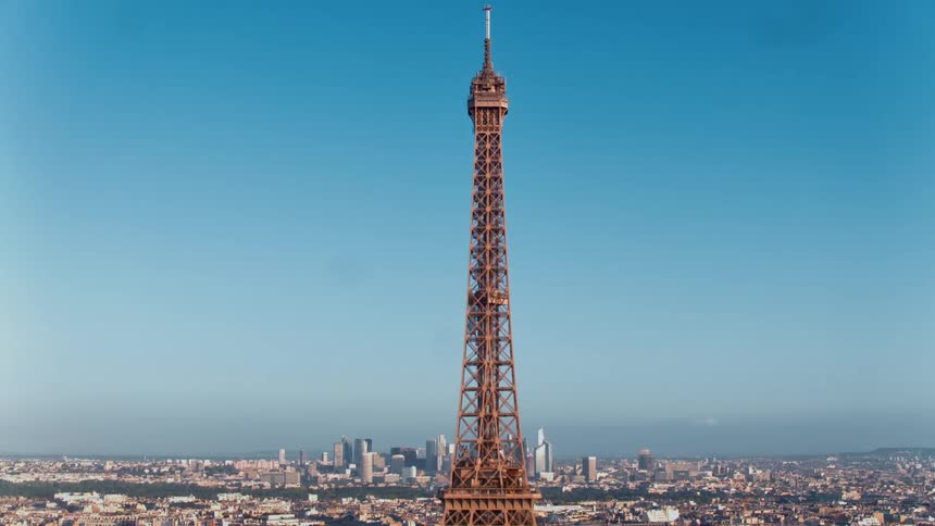 The sun shines upon a tall tower overlooking a city with the skyline in the distance