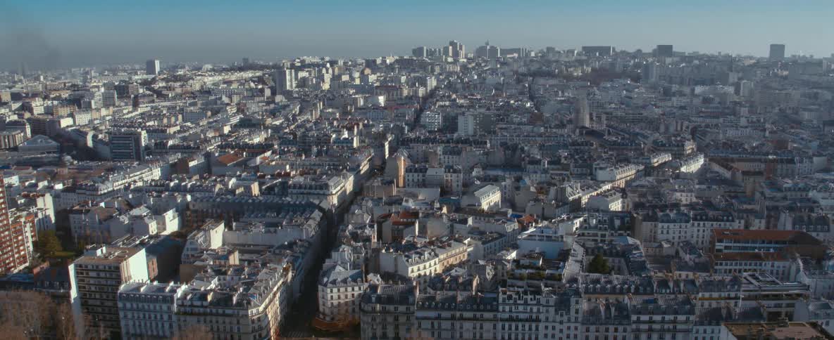 The sun shines upon a crowded city filled with buildings close together with spaces for roads and tall buildings and skyscrapers on the skyline in the distance