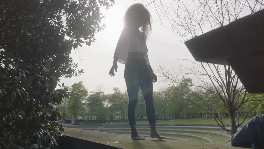 A woman walks toe to heel on the top of a wall