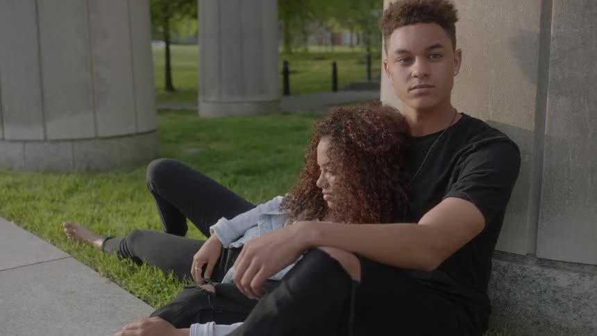 A woman lays in the arms of a seated man