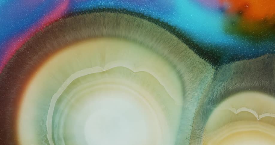 Expanding circles of abstract pearlescent ink drops flowing background