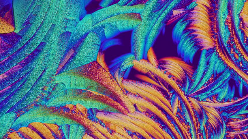 Colorful crystals growing and forming abstract shapes under microscope