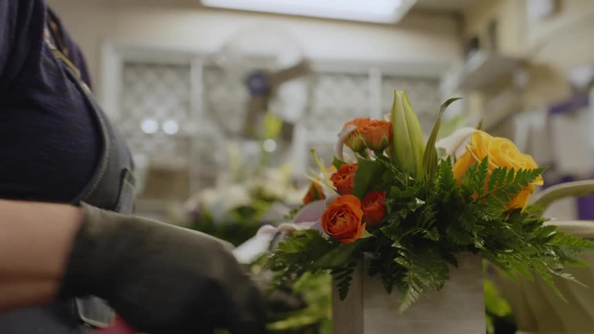 A florist is cutting flowers and arranging them in a box
