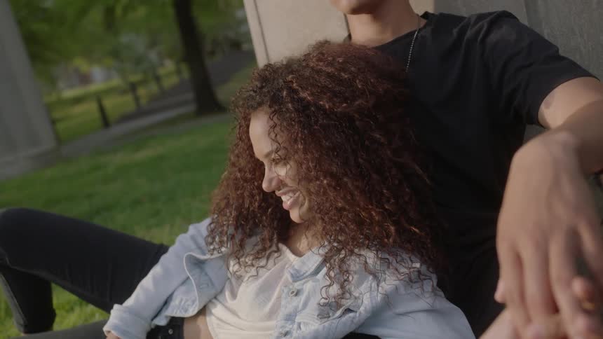 A woman lays on a man's lap on the grass