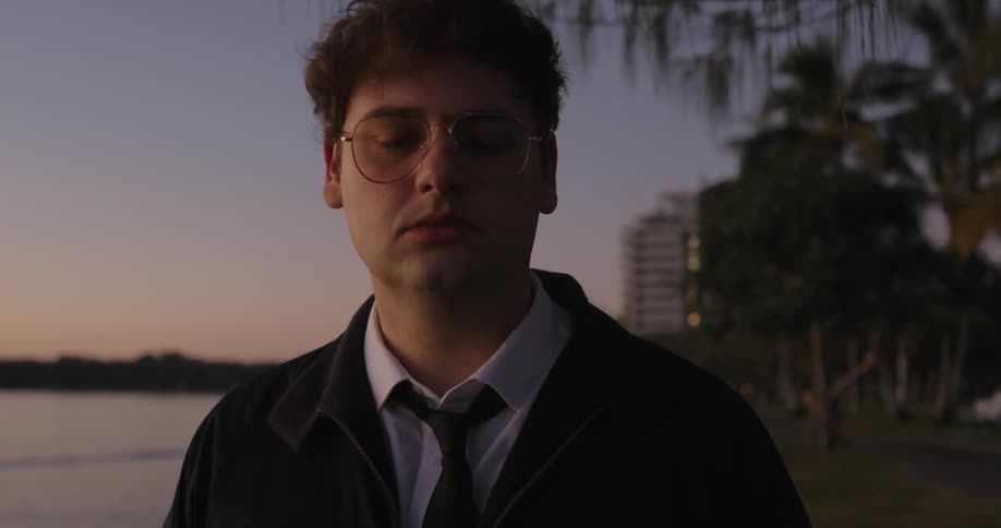 A man in a black tie and glasses staring straight ahead