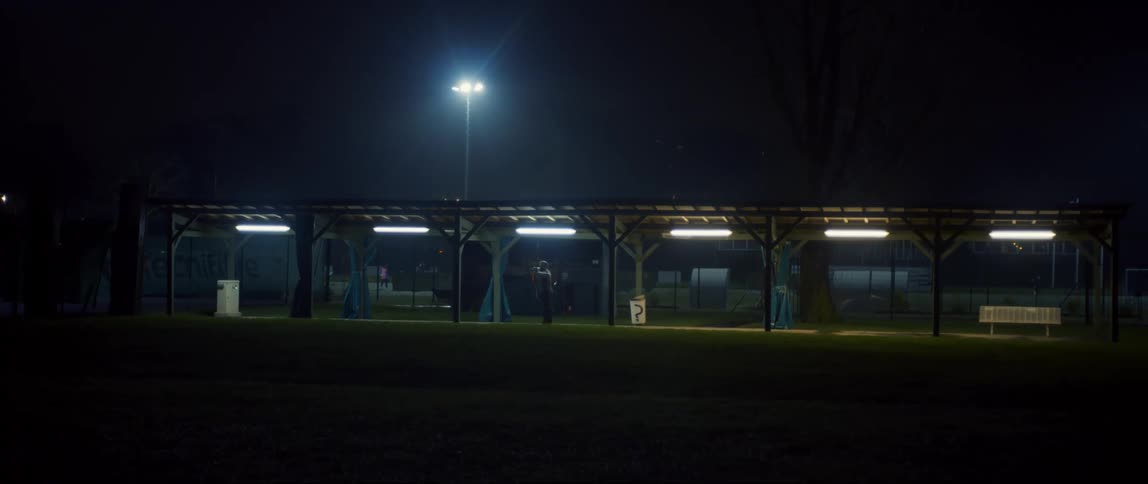A person standing on a covered path on a night with streetlights