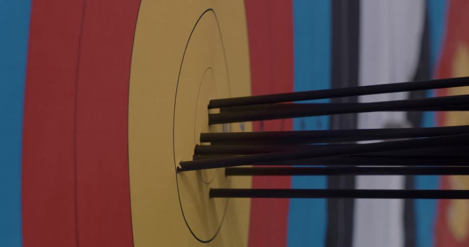 Closeup of a practice target made of paper with multiple arrows shot through it