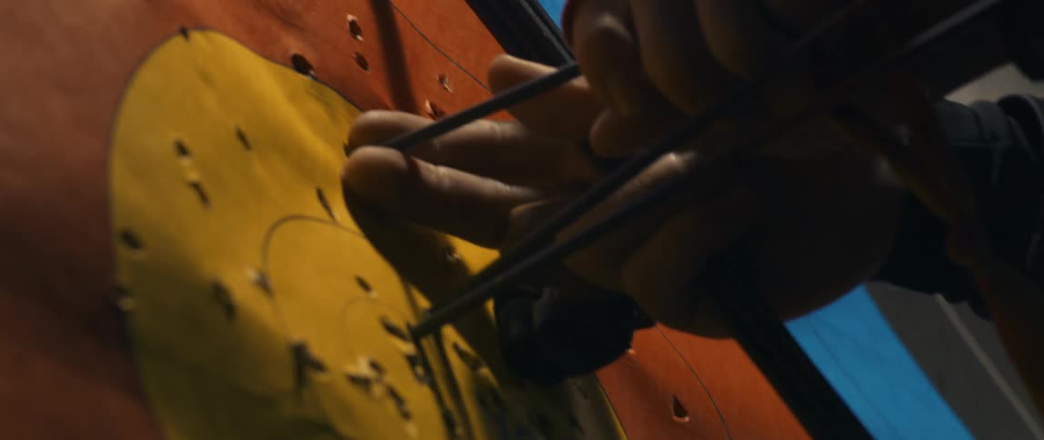 A mans hands pull arrows out of a paper dartboard