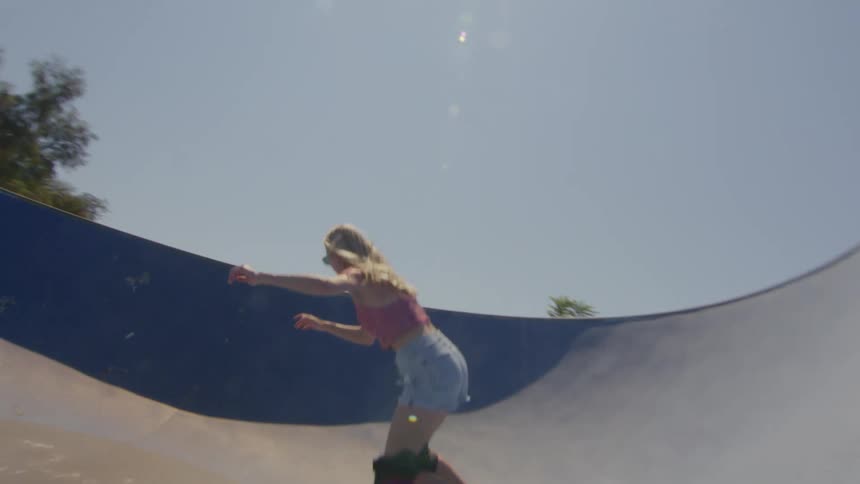Young blonde woman skateboarding in a circular ramp