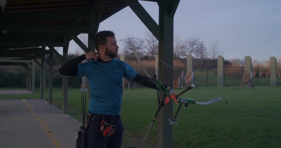 A man shoots an arrow with a bow on a target archery field