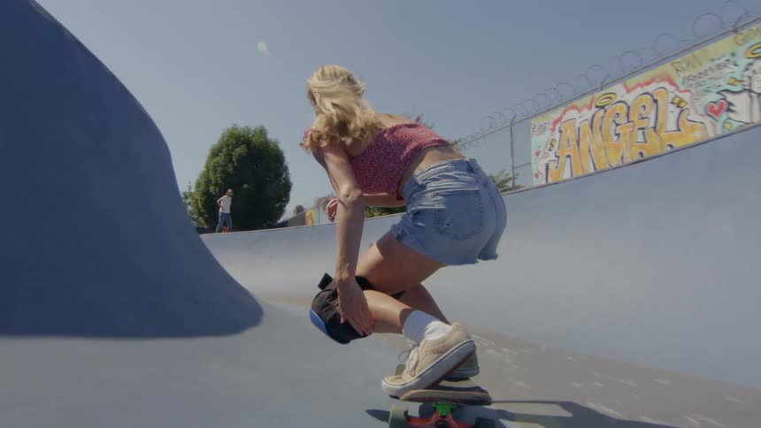 A blonde woman skateboarding on a small rink