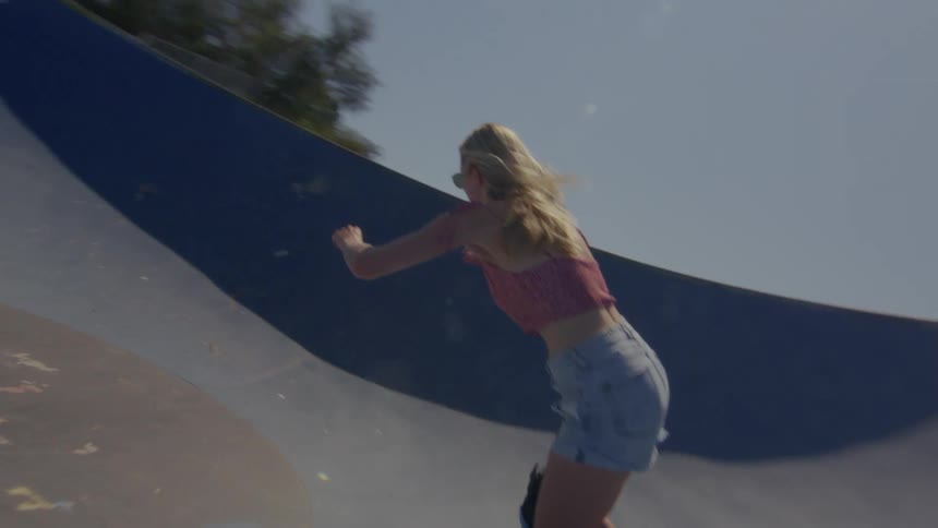 A young woman is skateboarding at a skate park in slow motion
