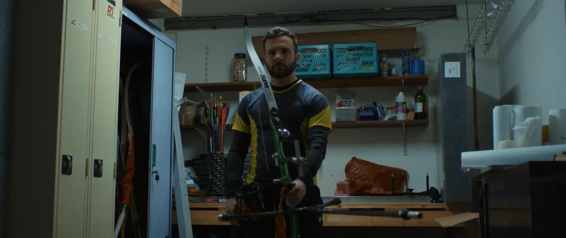 A man holding his bow and arrow with a serious facial expression