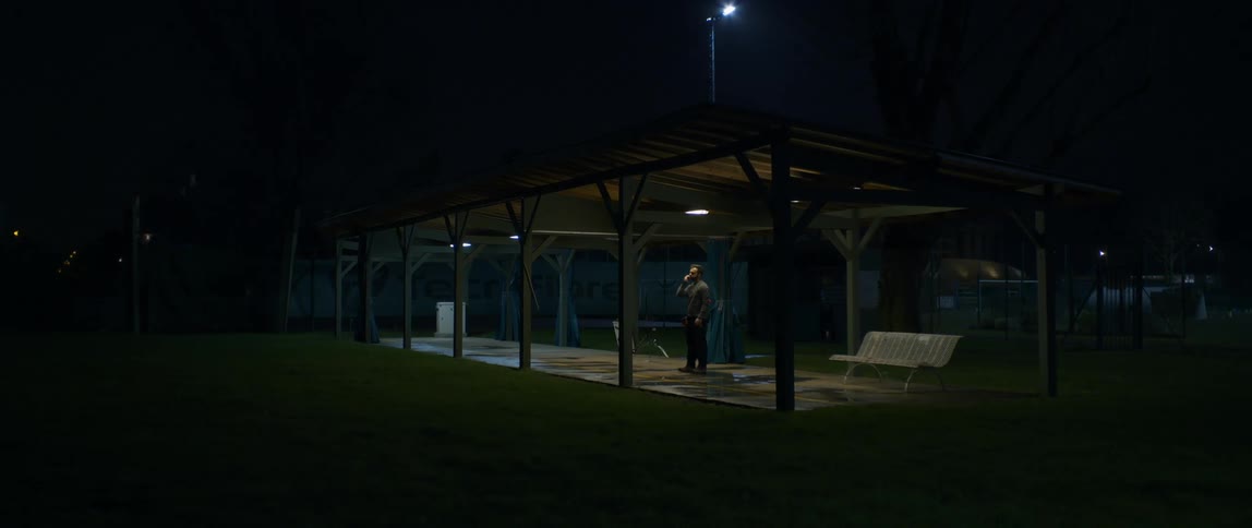 A man is warming up for training under a well lit pergola at night
