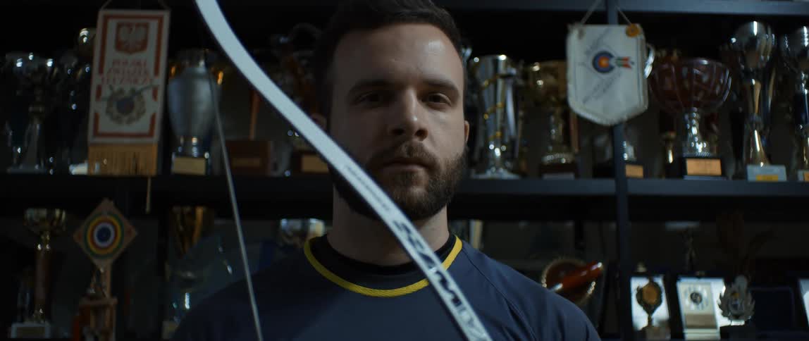 A man holds a bow while staring straight out