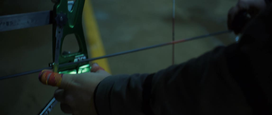 A bearded man placing an arrow on a bowstring