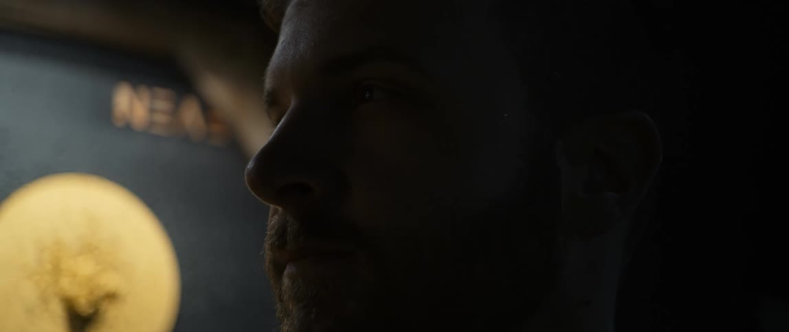The face of an adult man with a beard and a light behind him