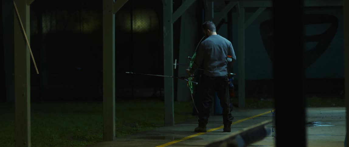 A man standing at a shooting range nocking an arrow on his bow