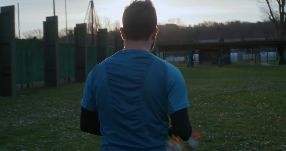 A man walking on grass at sunset with arrows at his back