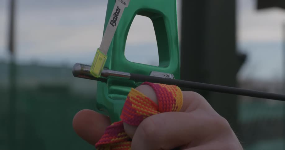 Archer aims arrow with strap wrapped fingers