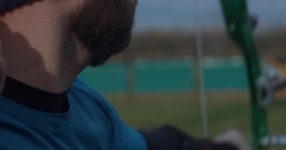 A man shoots an arrow with a compound bow across a sports field