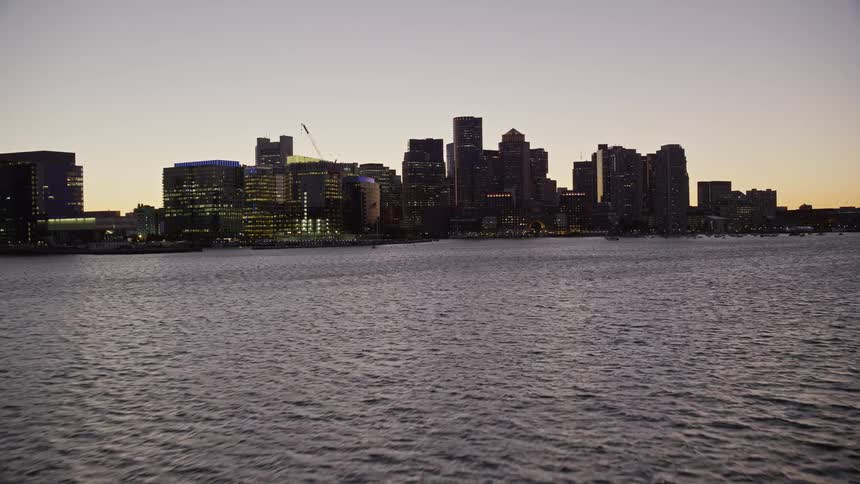 Aerial view of the skyline of a waterfront city next to the ocean at sunset