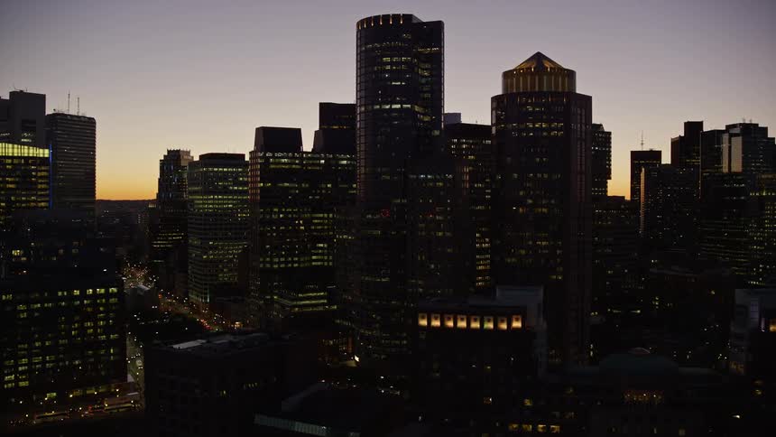 Several tall buildings in a city are dark on a clear morning