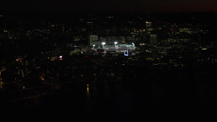 A stadium with bright lights on a night in a city