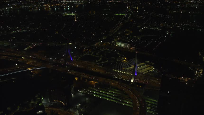 A bridge in a metropolitan city with several cars passing over it at night