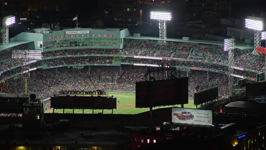 Aerial view of a baseball stadium full of people watching a baseball game at night