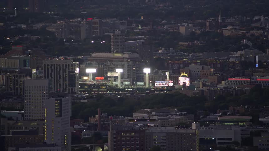 A stadium with bright lights in the middle of a nearby night city
