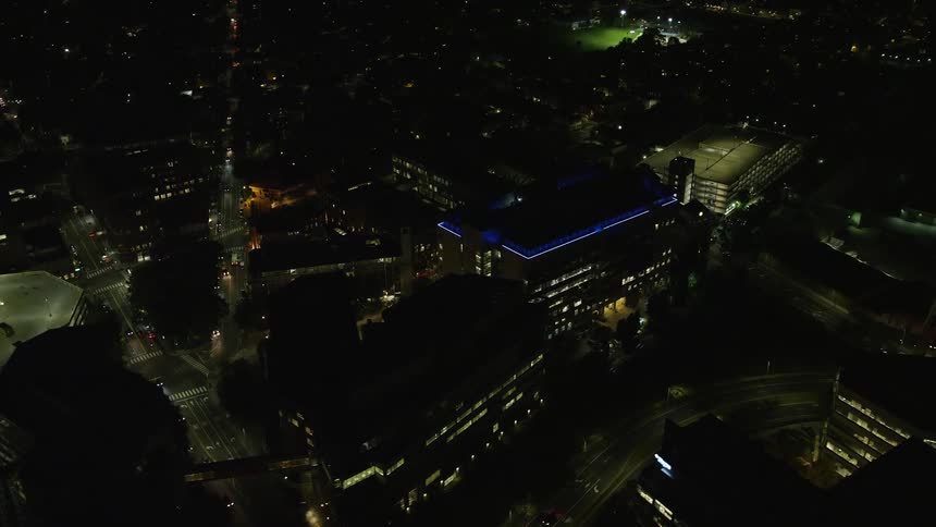 Building lights on at night with cars passing on the streets