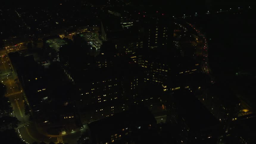 A night in a city with tall buildings and streets with few cars