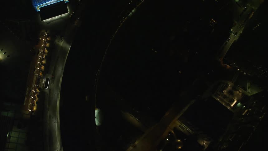 A city seen from above at night with some cars passing on the streets