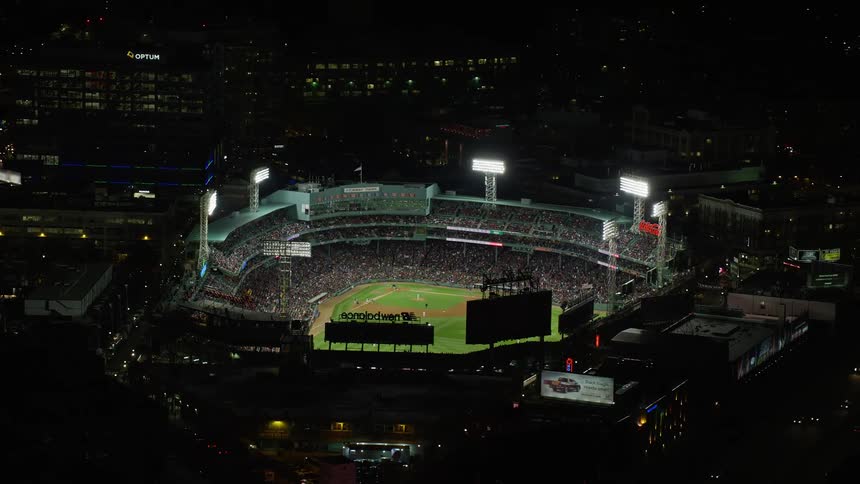 A baseball stadium filled with people in a city at night