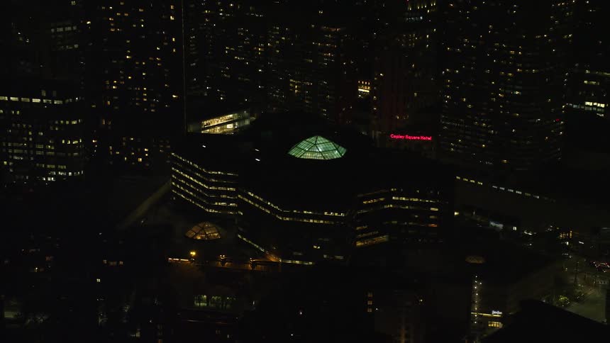 An aerial at night of an urban building with a glass dome on the rooftop