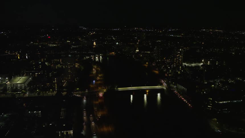 Traffic moves along city highways near river at night