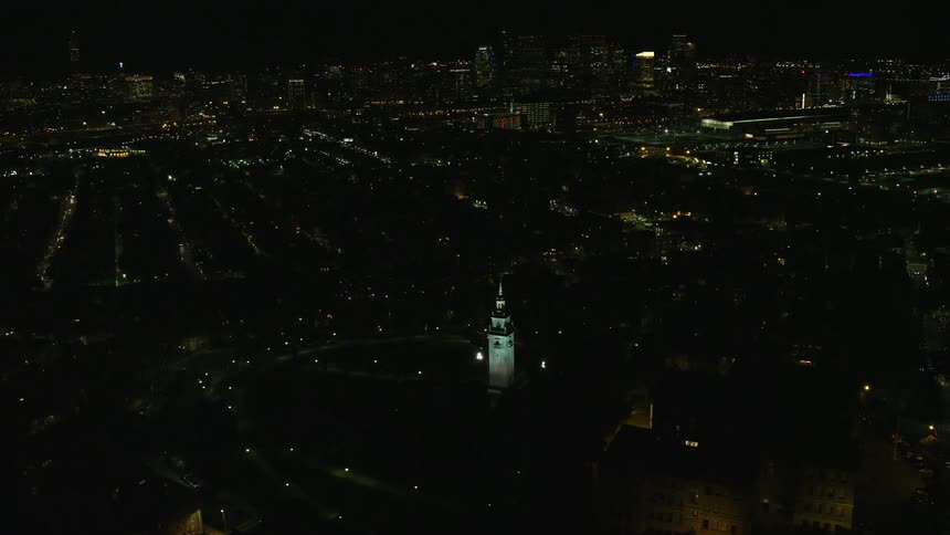 Aerial view of a metropolitan city at night with a centrally illuminated tower