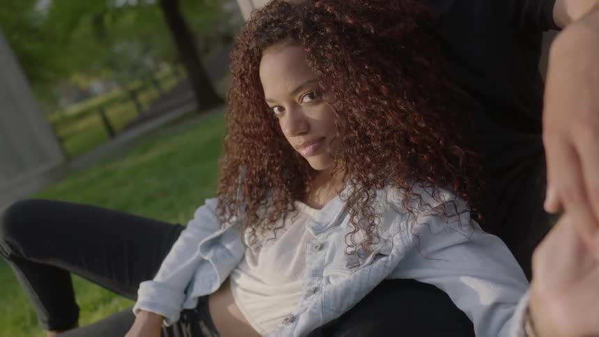 A woman is holding hands with someone sitting on the grass