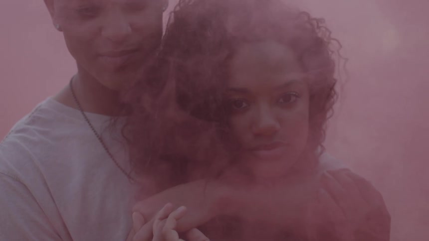 A man is hugging a woman with pink smoke surrounding them