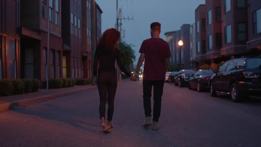 A man and woman hold hands walking down the street
