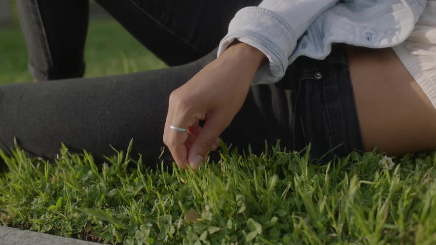 A woman is playing with the grass laying down