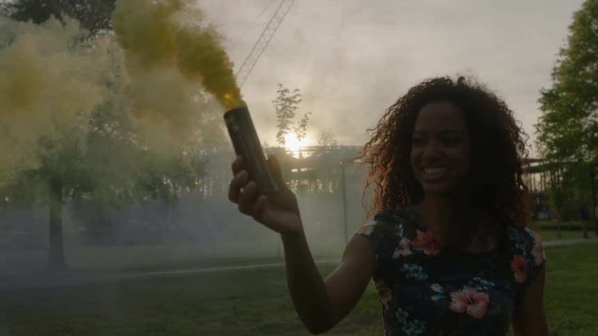 A woman is holding a can with yellow smoke coming out of it