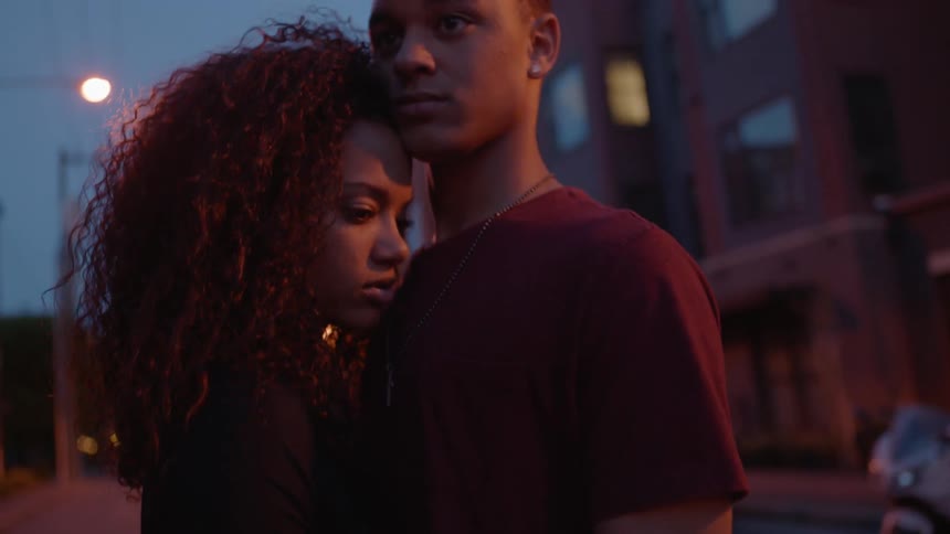 A man and woman lean on each other in the street