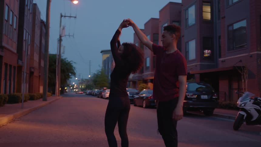 Two people dance in the street at dawn